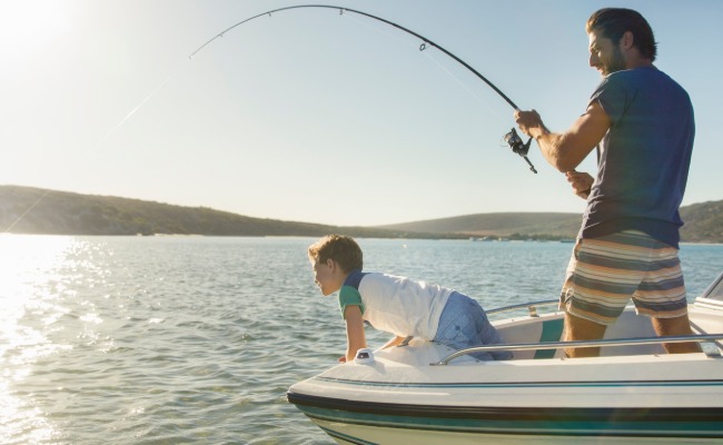 Man catching fish with child on dual console 