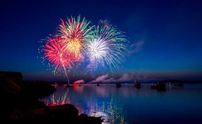 Fireworks over water with boats anchored beneath